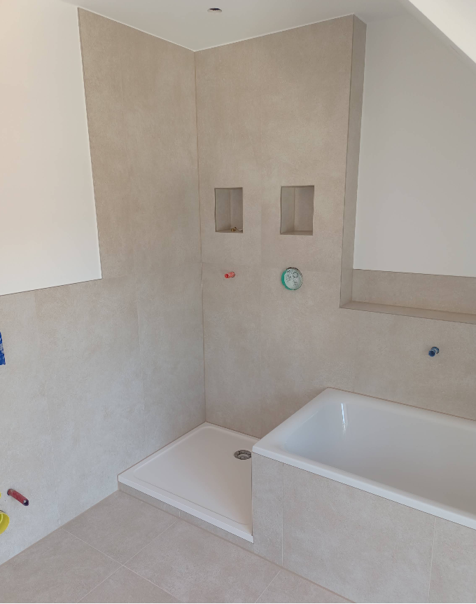 Dachgeschossbad mit Badewanne, bodengleicher Dusche und zwei Wandnischen in Sandoptik