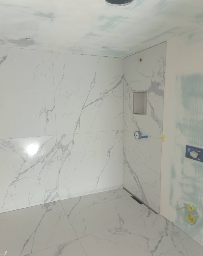 Bodengleiche Dusche mit weißen Großformatplatten in Marmoroptik und Wandnische