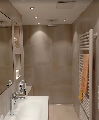 Bad in Sandbeige mit bodengleicher Dusche, Waschtisch und beleuchteter Wandnische