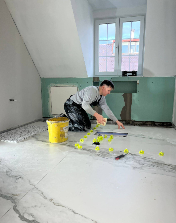 Fliesenleger A. Schatzki beim Verlegen großformatiger Platten mit Nivelliersystem